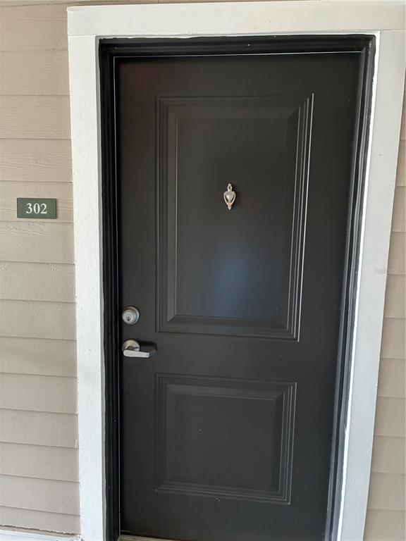 A dark-colored front door with a silver knocker and handle is labeled with the number 302 — 2280 WATERFALL COURT UNIT 4-302, MOUNT DORA, FL