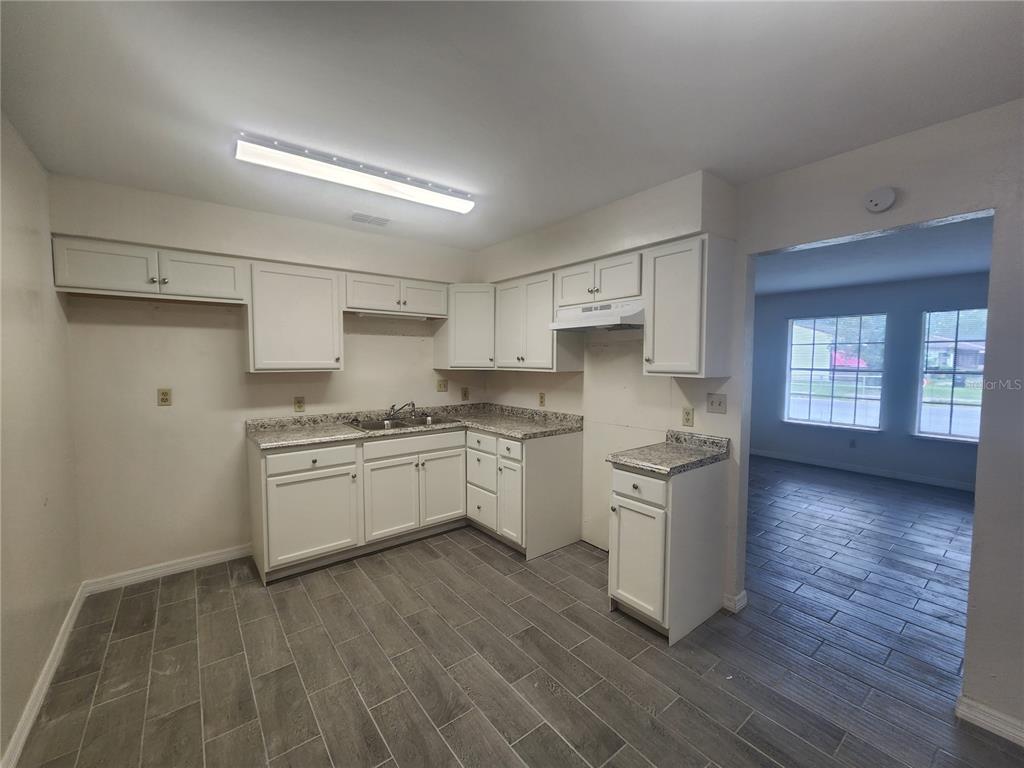 A kitchen with white cabinets, granite countertops, and gray wood-look tile flooring — 5817 NW 23 TERRACE UNIT 2, GAINESVILLE, FL