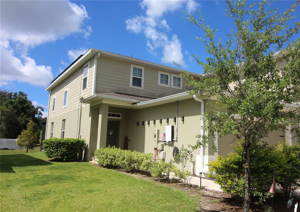 A two-story townhouse with light green stucco and tan siding under a blue sky — 2135 LACEFLOWER DRIVE, BRANDON, FL