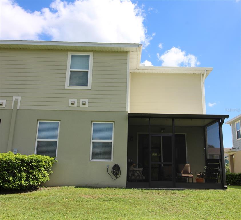 The exterior of a two-story townhouse features a screened-in patio and a grassy yard — 2135 LACEFLOWER DRIVE, BRANDON, FL