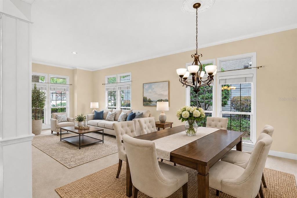 A bright, open-concept living and dining room with neutral walls, carpeted floors, and large windows — 10310 SW 51ST LANE, GAINESVILLE, FL