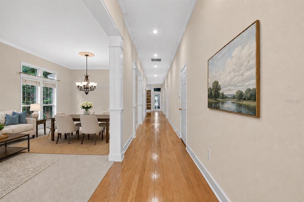 A long hallway with hardwood floors leads past a dining area toward a glass door — 10310 SW 51ST LANE, GAINESVILLE, FL
