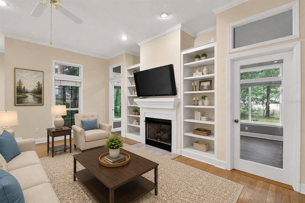 A living room features a fireplace with built-in shelves, a ceiling fan, and glass doors — 10310 SW 51ST LANE, GAINESVILLE, FL