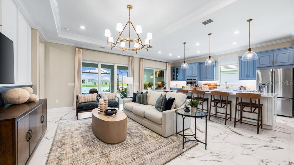 An open-concept living room and kitchen featuring marble floors, blue cabinetry, and a large chandelier — 26124 ASPARANO AVENUE, ENGLEWOOD, FL