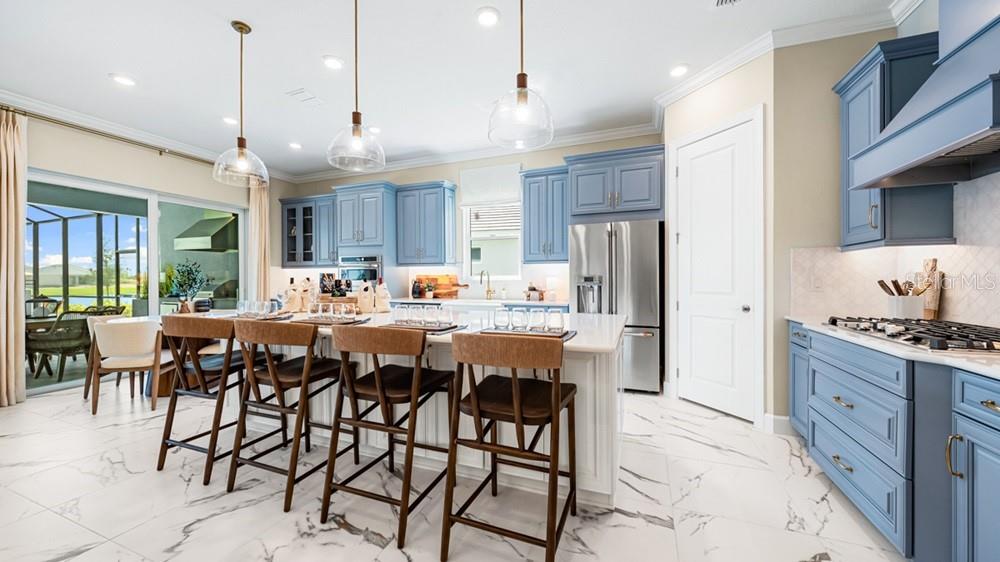 A kitchen features blue cabinets, a white island with bar stools, and marble-look tile flooring — 26124 ASPARANO AVENUE, ENGLEWOOD, FL