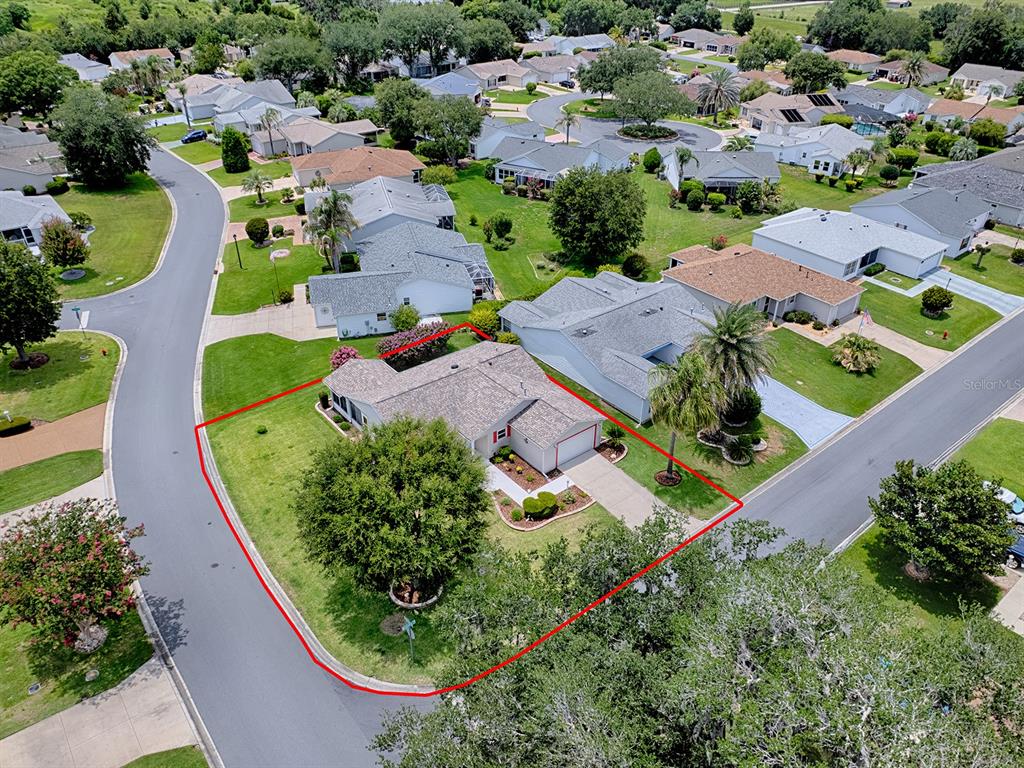 An aerial view shows a single-story house with a gray roof on a corner lot — 1070 BERKSHIRE PLACE, THE VILLAGES, FL