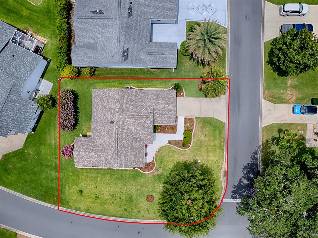 An aerial view shows a residential property with a house, driveway, and landscaped yard — 1070 BERKSHIRE PLACE, THE VILLAGES, FL
