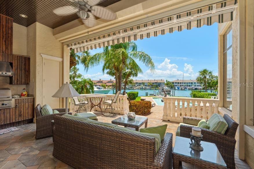 A covered patio with outdoor furniture overlooks a swimming pool and a marina with boats — 841 PONCE DE LEON DRIVE, ST PETERSBURG, FL