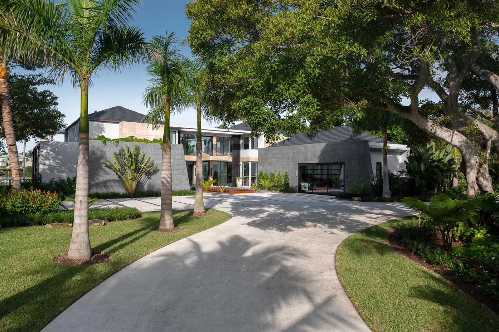 A modern house with gray stone walls and a concrete driveway surrounded by palm trees — 488 S Beach Road, Jupiter Island FL 33455, JUPITER ISLAND, FL