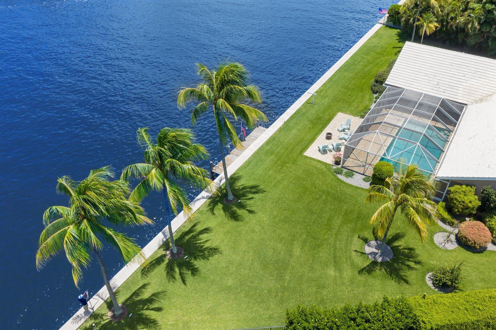 An aerial view shows a waterfront backyard with palm trees, a pool, and a patio — 970 Orchid Lane, Gulf Stream FL 33483, GULF STREAM, FL