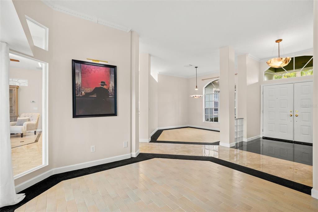 An entryway with light wood flooring, a black border, and a framed painting on the wall — 5501 STAG THICKET LANE, PALM HARBOR, FL