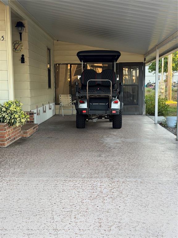 A covered concrete carport features a golf cart parked in front of a home entrance — 4165 ROLLING OAKS DRIVE, WINTER HAVEN, FL
