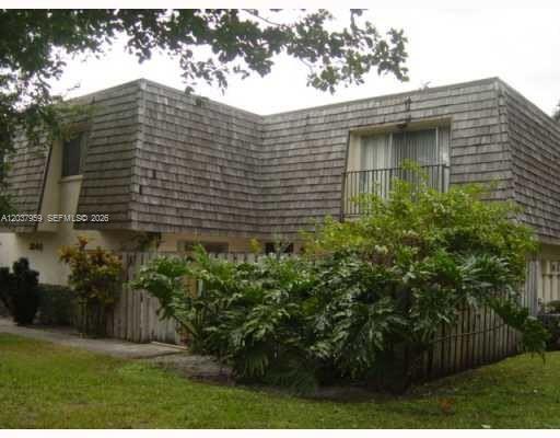 A two-story building with wood-shingled siding, a balcony, and a fenced-in patio area — 2060 SW 90th Ave # 18, Davie FL 33324, DAVIE, FL