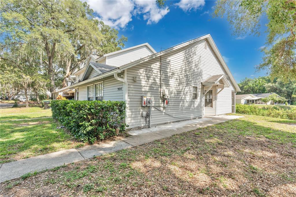 The exterior of a light-colored vinyl-sided house features a small concrete walkway and landscaping — 9616 RIVER WALK COURT, ORLANDO, FL