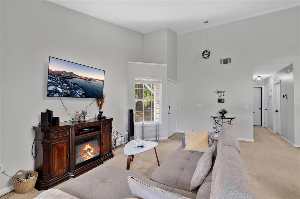 A living room features a fireplace console, a grey sectional sofa, and a high ceiling — 9616 RIVER WALK COURT, ORLANDO, FL