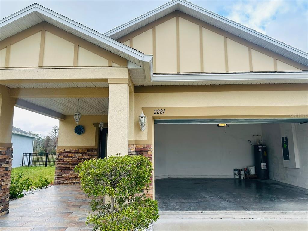A view of a house exterior featuring a stone-accented pillar and an open garage — 2221 CANYON BREEZE AVENUE, KISSIMMEE, FL