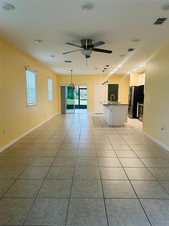 An open-concept living and kitchen area features light yellow walls and large floor tiles — 2221 CANYON BREEZE AVENUE, KISSIMMEE, FL