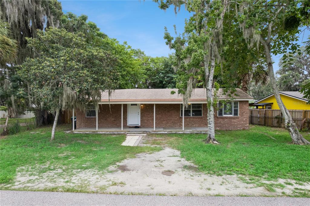 A single-story brick house with a covered front porch sits behind a grassy yard — 3625 COCHRAN STREET, APOPKA, FL