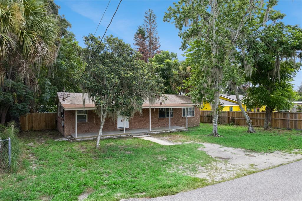 A single-story brick house with a front porch sits on a grassy lot with trees — 3625 COCHRAN STREET, APOPKA, FL