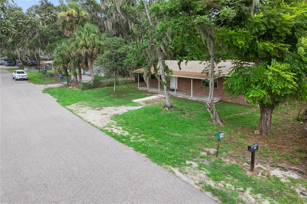 A single-story brick house with a front porch sits on a grassy lot with trees — 3625 COCHRAN STREET, APOPKA, FL