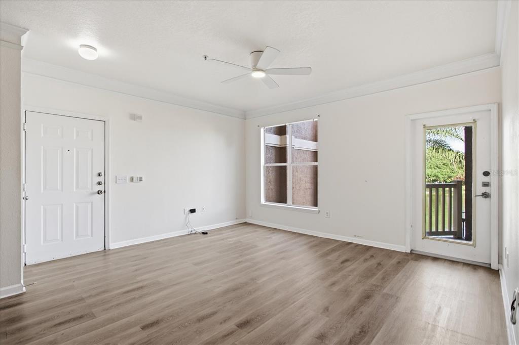 An empty room with light wood-look flooring, a ceiling fan, a window, and two doors — 8849 VILLA VIEW CIRCLE UNIT 203, ORLANDO, FL