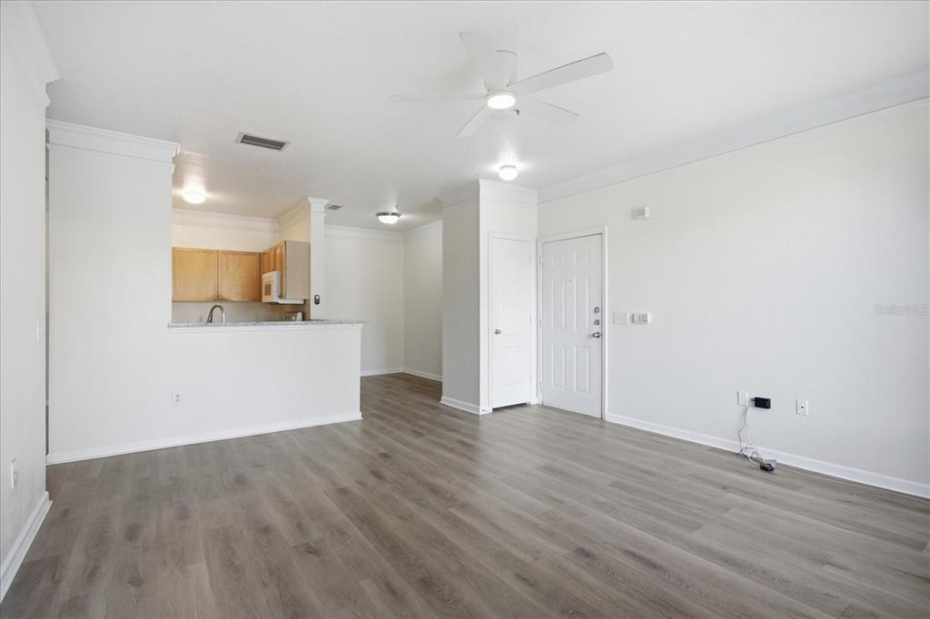 An open-concept living area features light wood-look flooring, white walls, and a kitchen pass-through — 8849 VILLA VIEW CIRCLE UNIT 203, ORLANDO, FL