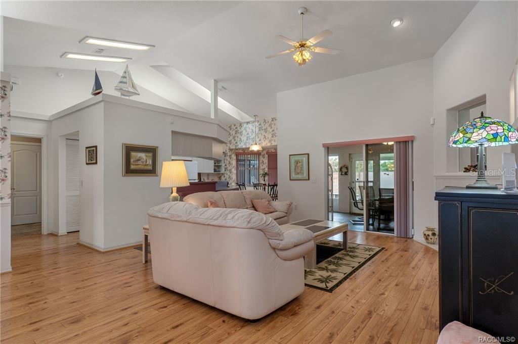 A living room with light wood flooring, a white sofa, and a vaulted ceiling — 1000 S BROOKFIELD DRIVE, LECANTO, FL