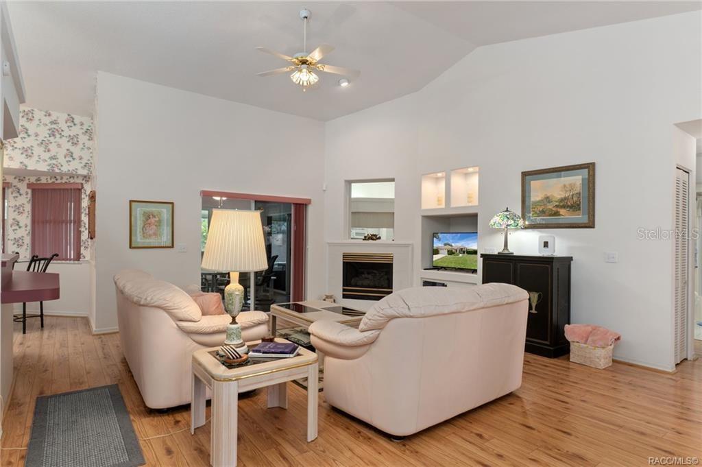 A living room features light-colored sofas, a fireplace, built-in shelving, and wood-look flooring — 1000 S BROOKFIELD DRIVE, LECANTO, FL