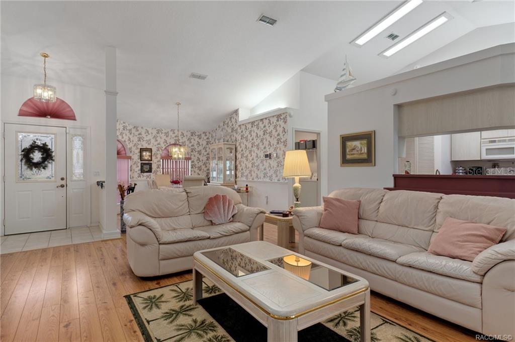 A living room features two white sofas, a coffee table, and floral wallpaper — 1000 S BROOKFIELD DRIVE, LECANTO, FL