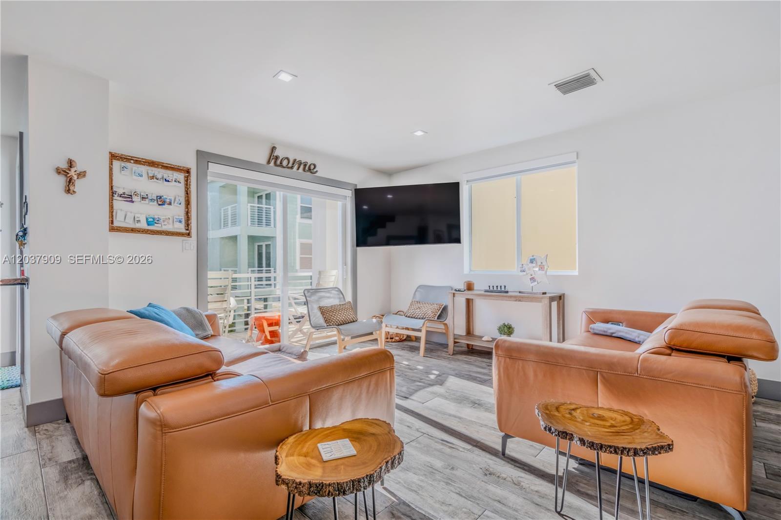 A living room features tan leather sofas, wood-slice side tables, and a wall-mounted television — 94825 Overseas #254, Key Largo FL 33037, KEY LARGO, FL