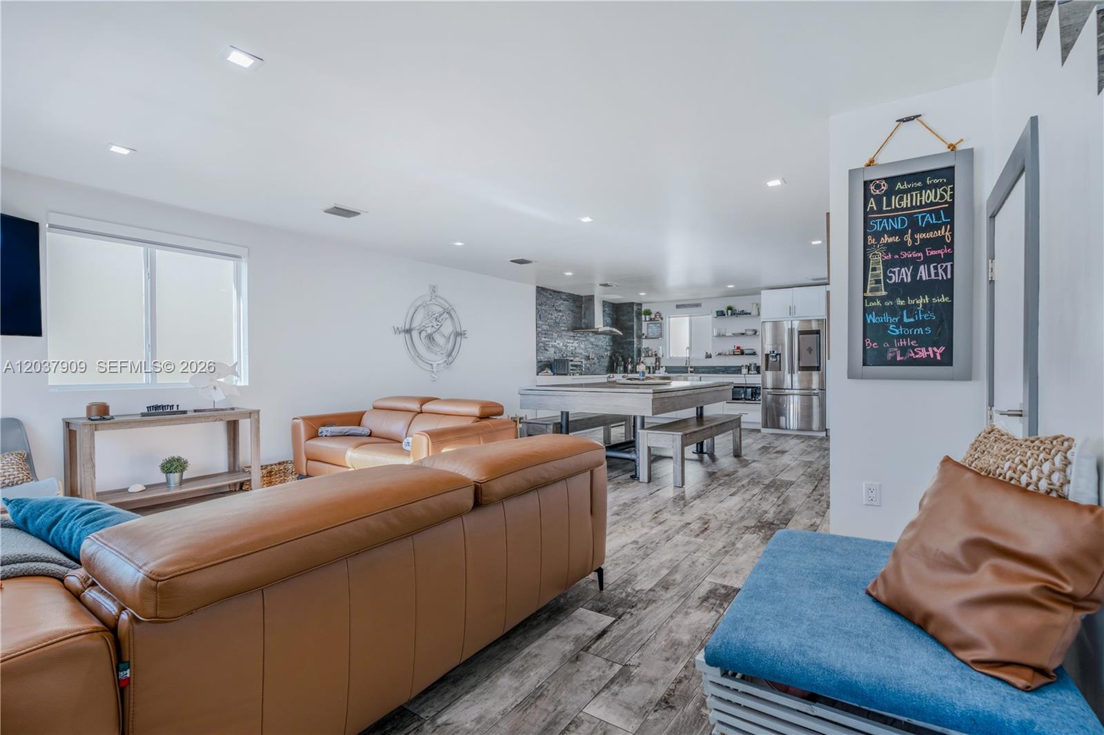 An open-concept living room and kitchen feature leather sofas, wood-look flooring, and a dining island — 94825 Overseas #254, Key Largo FL 33037, KEY LARGO, FL