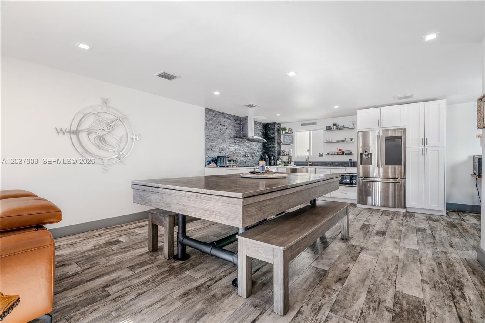 A kitchen and dining area features a wooden table with benches, stainless steel appliances, and stone-tiled walls — 94825 Overseas #254, Key Largo FL 33037, KEY LARGO, FL