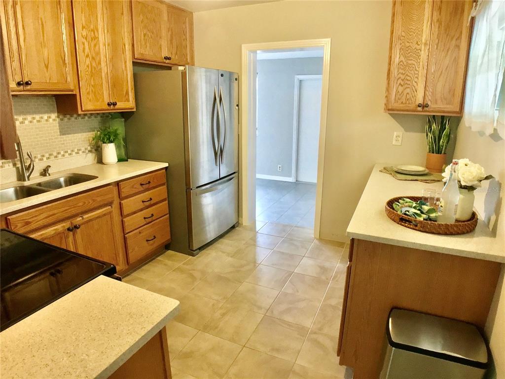 A kitchen with wood cabinets, stainless steel appliances, tile flooring, and light-colored countertops — 3809 W VASCONIA STREET, TAMPA, FL