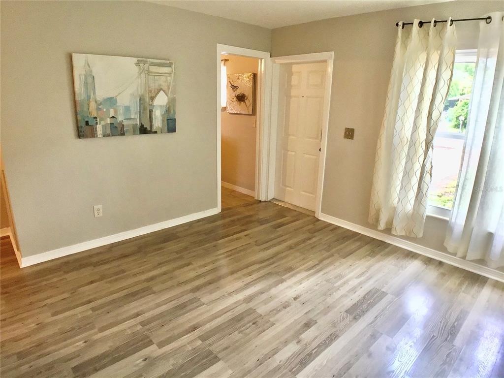 A room with light gray walls, wood-look flooring, a window with curtains, and two doorways — 3809 W VASCONIA STREET, TAMPA, FL