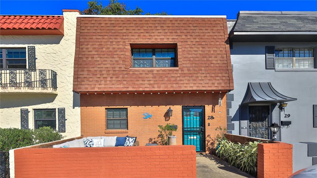 A two-story townhouse with a brick facade, a mansard roof, and a front patio — 625 N HALIFAX AVENUE UNIT 28, DAYTONA BEACH, FL