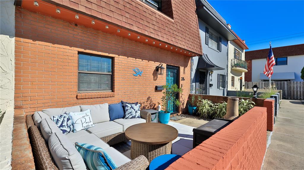 A brick patio features a sectional sofa, a round table, and a low privacy wall — 625 N HALIFAX AVENUE UNIT 28, DAYTONA BEACH, FL