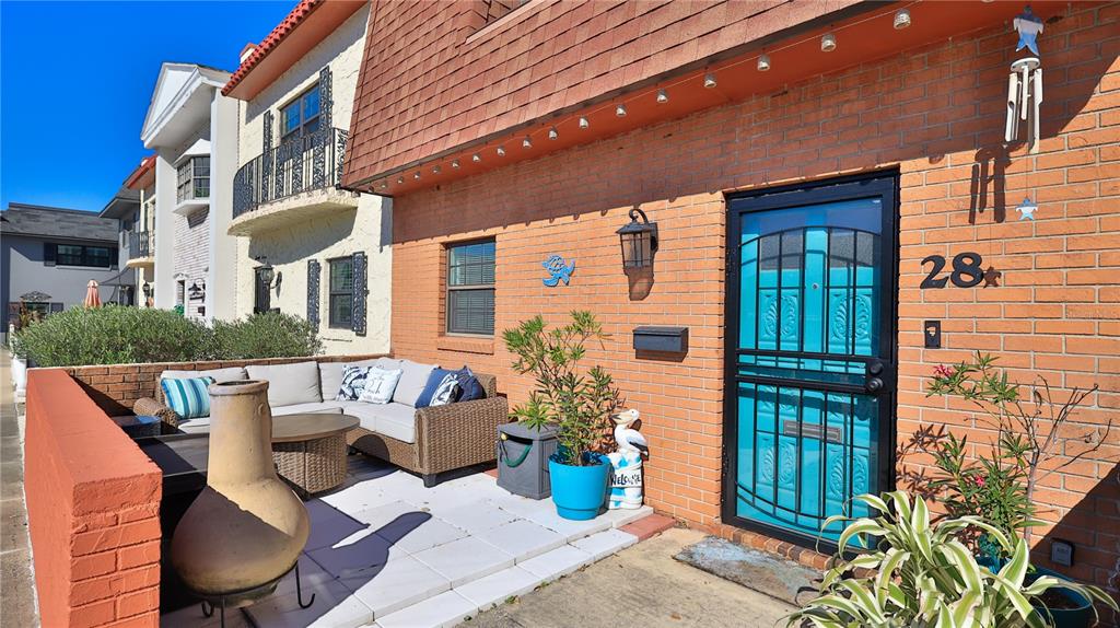 A brick exterior home features a patio with outdoor seating and a bright blue door — 625 N HALIFAX AVENUE UNIT 28, DAYTONA BEACH, FL