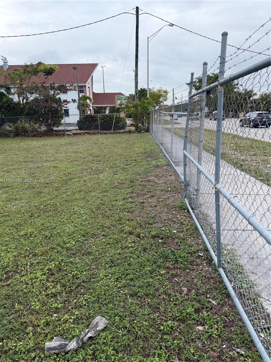 A grassy vacant lot is bordered by a chain-link fence and a paved sidewalk — 752 Opa Locka Blvd, Miami FL 33168, MIAMI, FL