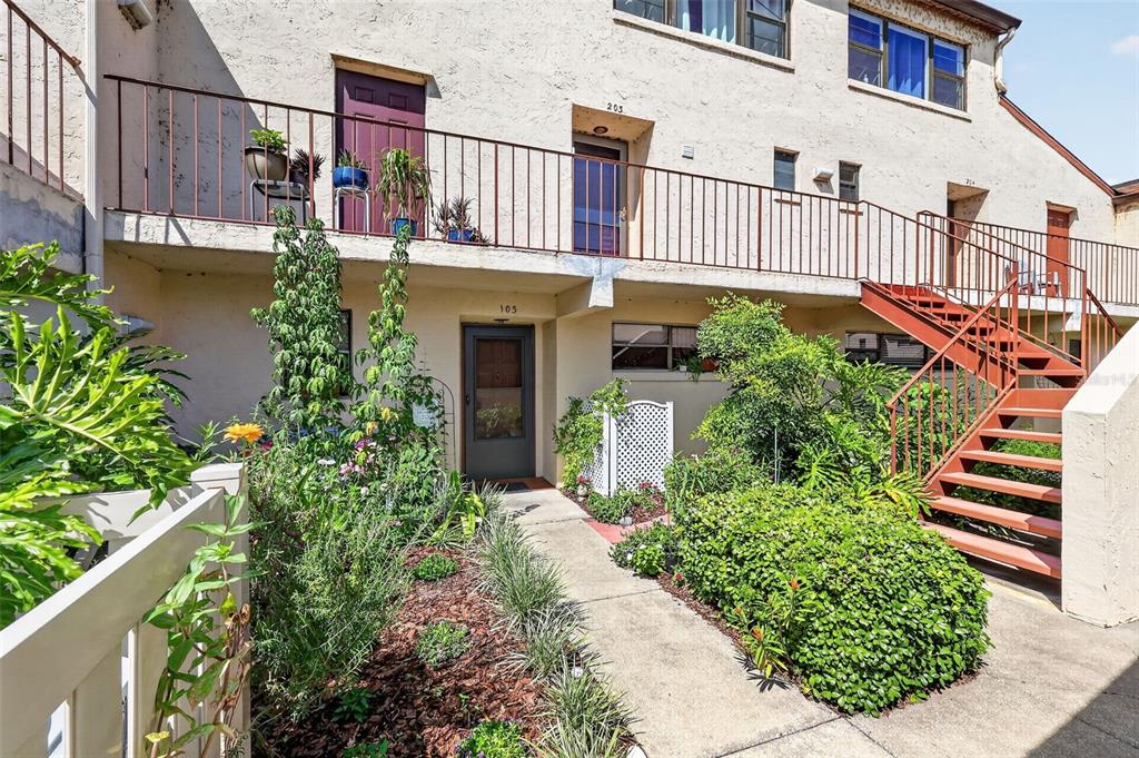An exterior view of a two-story apartment building with a walkway, stairs, and landscaping — 4300 BAYWOOD BOULEVARD UNIT A103, MOUNT DORA, FL