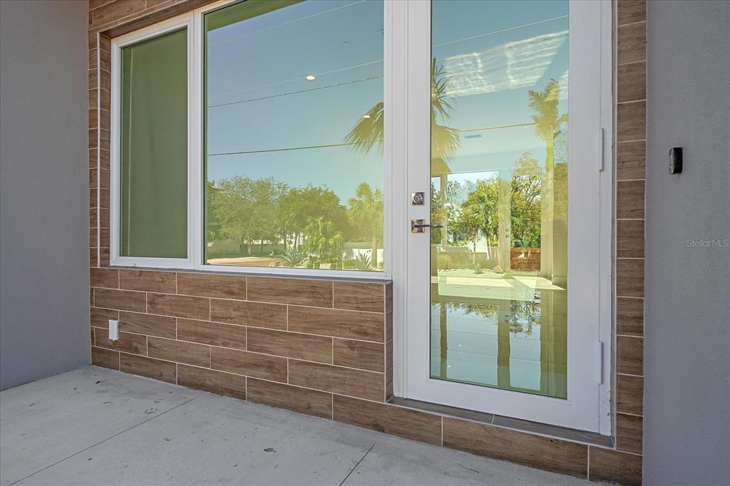 A white glass door and window set against a brown wood-look tiled exterior wall — 1720 ALDERMAN STREET, SARASOTA, FL