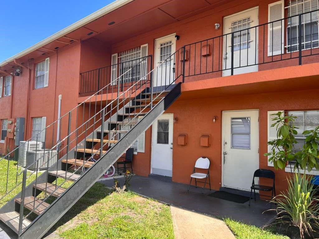 An exterior view of a two-story apartment building with a metal staircase and orange stucco — 1665 W OAK RIDGE ROAD UNIT C, ORLANDO, FL