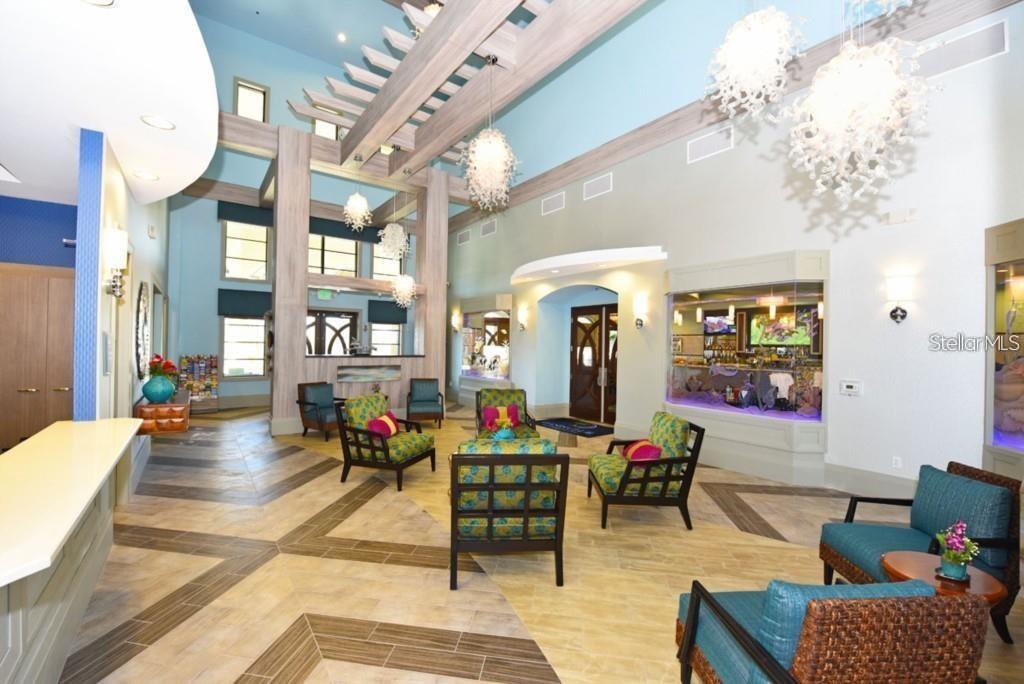 A spacious lobby features a large aquarium, patterned armchairs, and high ceilings with decorative lighting — 1551 OBSERVER LANE, DAVENPORT, FL