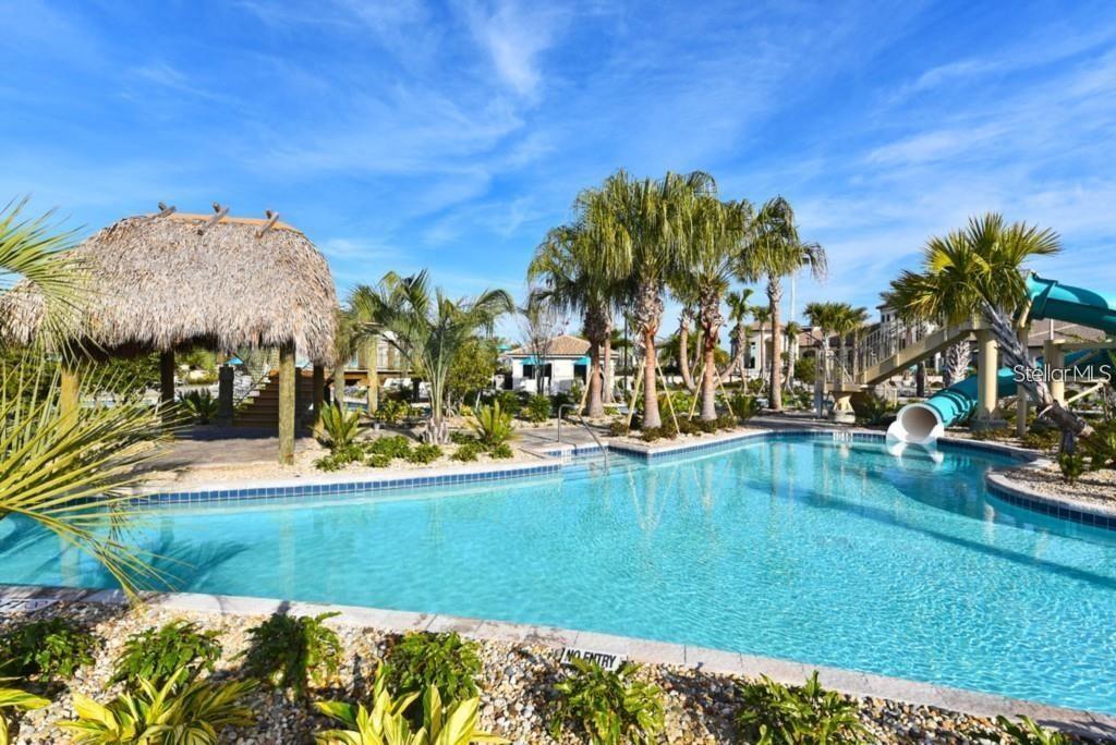 A swimming pool with a water slide and a thatched-roof cabana under a blue sky — 1551 OBSERVER LANE, DAVENPORT, FL