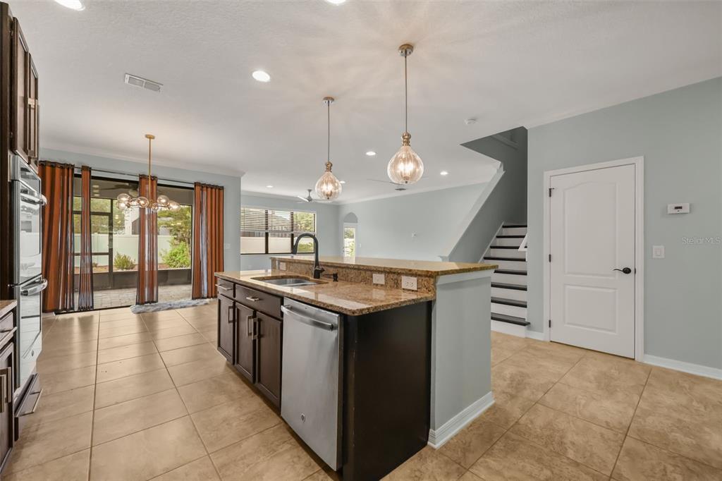 A kitchen with dark cabinets, granite countertops, stainless steel appliances, and tile flooring — 5729 RUE GALILEE LANE, SANFORD, FL
