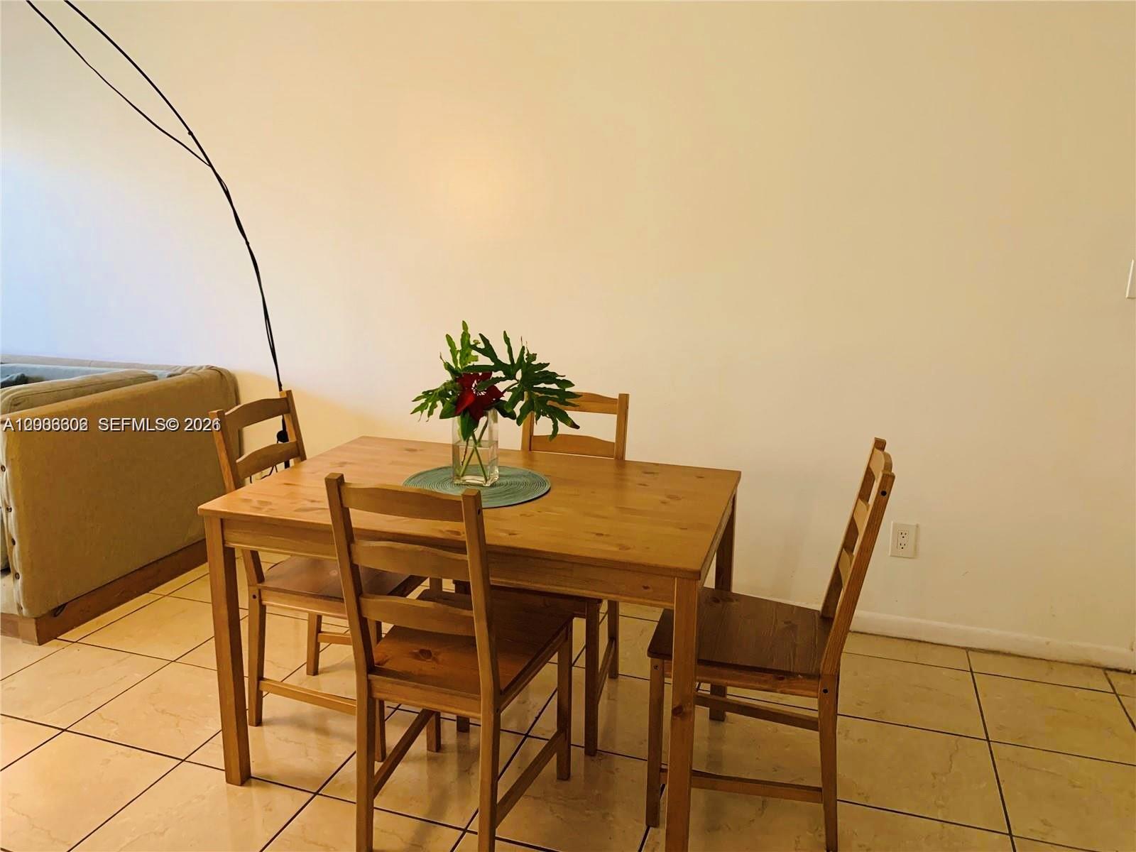A wooden dining table with four chairs sits on a light-colored tiled floor — 5855 Washington St # 90, Hollywood FL 33023, HOLLYWOOD, FL