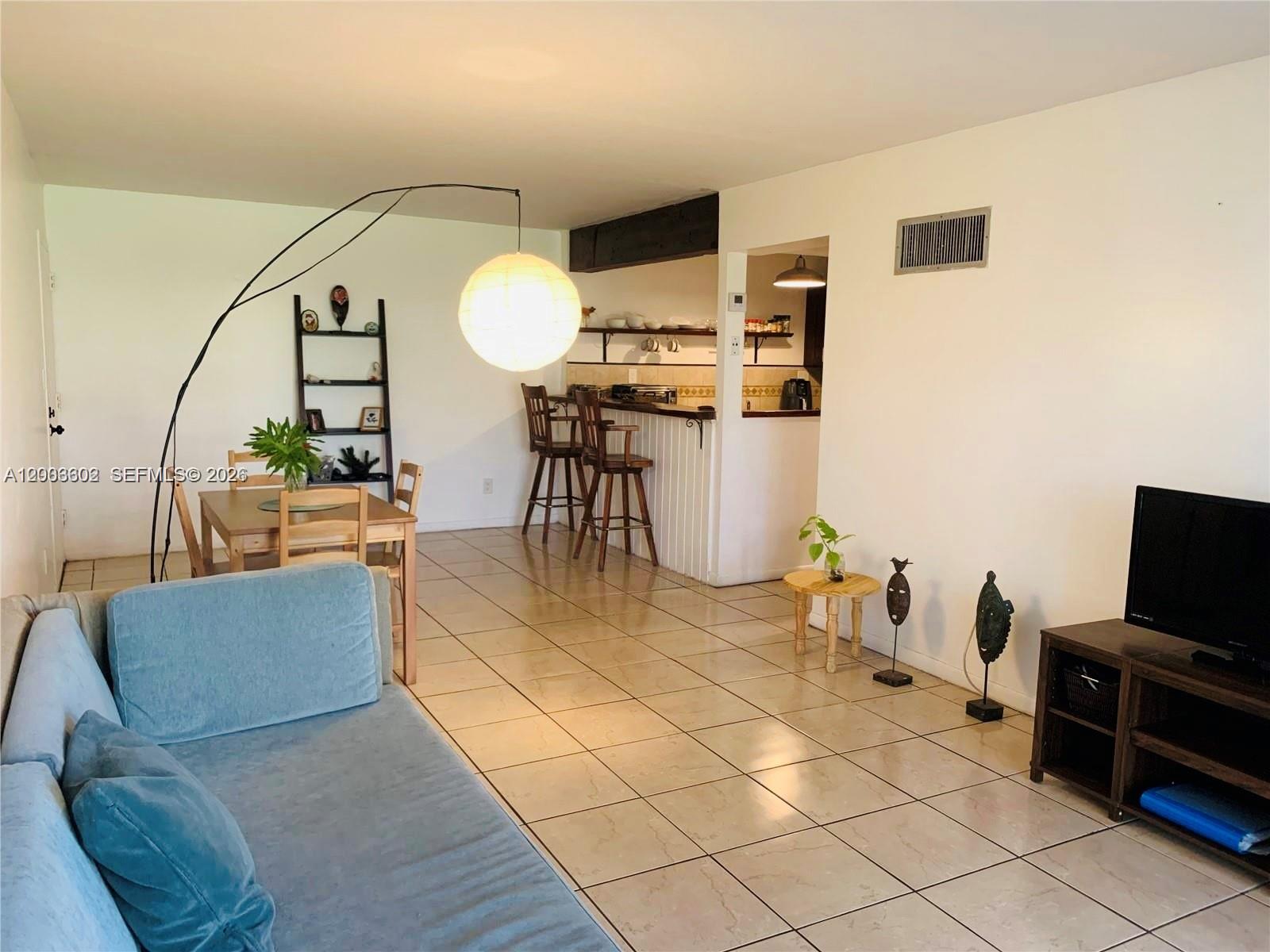 This open-concept living and dining area features tiled floors and a breakfast bar — 5855 Washington St # 90, Hollywood FL 33023, HOLLYWOOD, FL