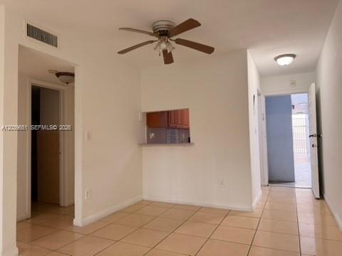 An interior view of a tiled room featuring a ceiling fan and a kitchen pass-through — 2400 NW 22nd Ct # 3, Miami FL 33142, MIAMI, FL