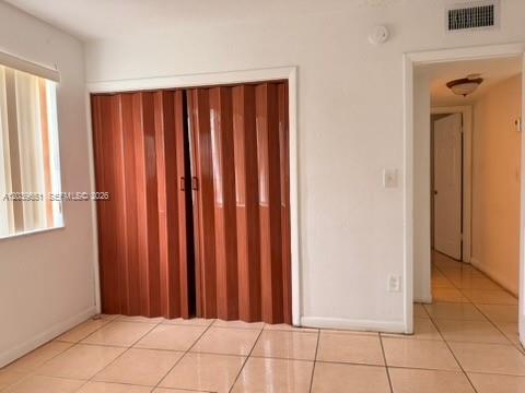 A room with tiled floors, a folding closet door, and a hallway leading to another room — 2400 NW 22nd Ct # 3, Miami FL 33142, MIAMI, FL