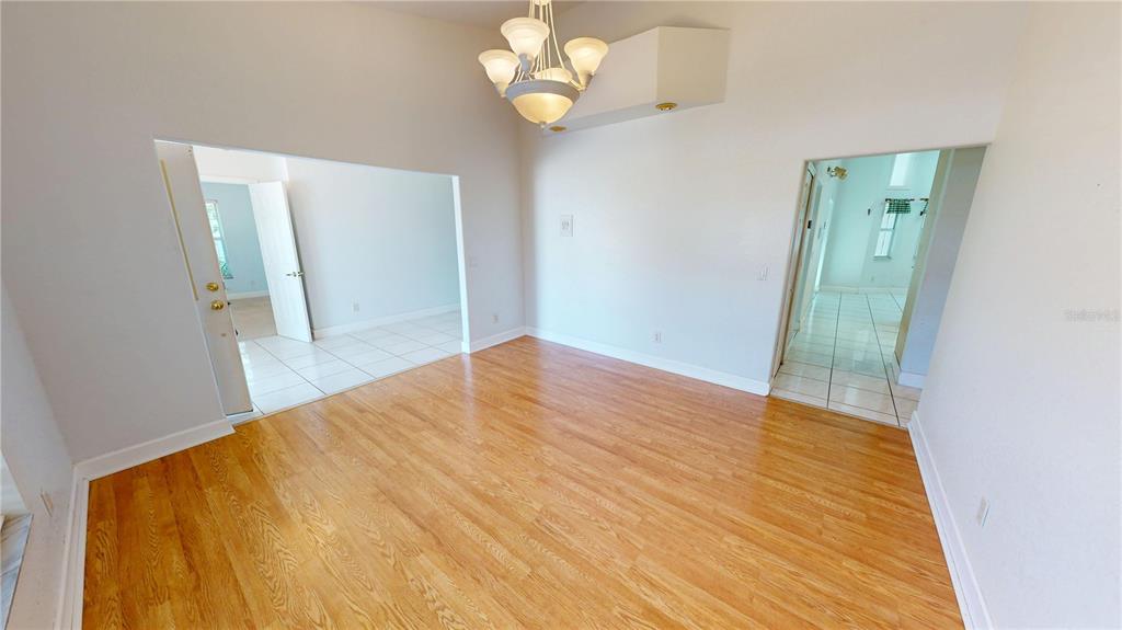 A room with light wood flooring, a chandelier, and doorways leading to tiled areas — 2244 MAURITANIA ROAD, PUNTA GORDA, FL
