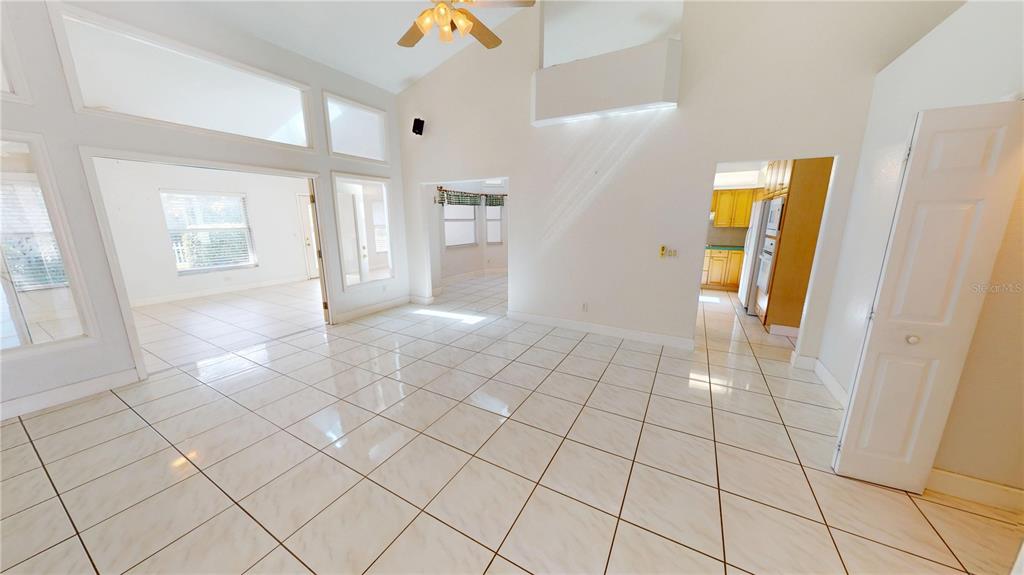 A bright living area with white tiled floors, high ceilings, and an adjacent kitchen — 2244 MAURITANIA ROAD, PUNTA GORDA, FL